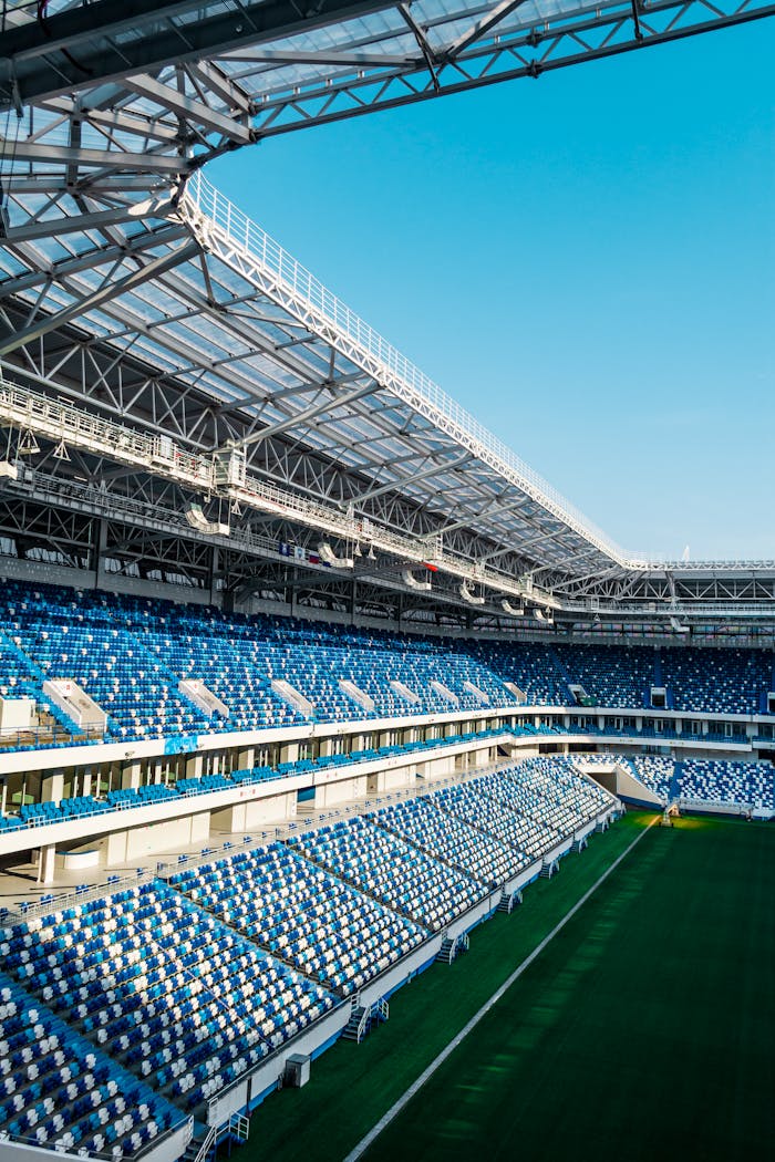 Spacious modern soccer stadium with blue seating and open sky view.