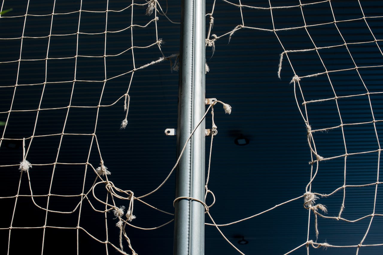Detailed view of a torn sports net, highlighting wear and age.